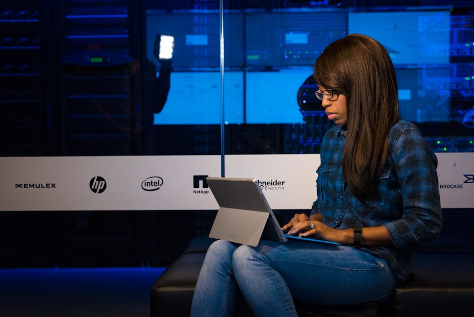 Professional woman working on laptop in a server room, showcasing technology and remote work