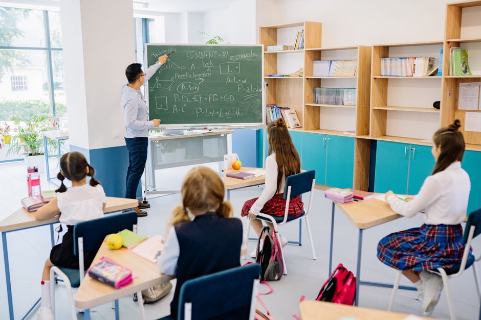 Children in a classroom focused on a math lesson with a teacher.