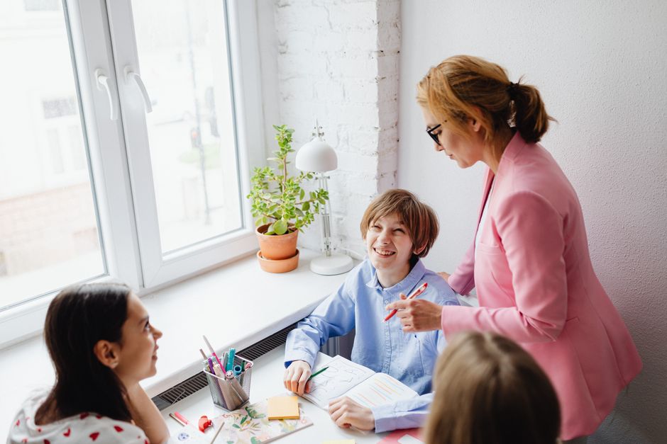 A teacher guides students in a bright, collaborative classroom environment.